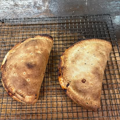 Two golden calzones on a cooling rack