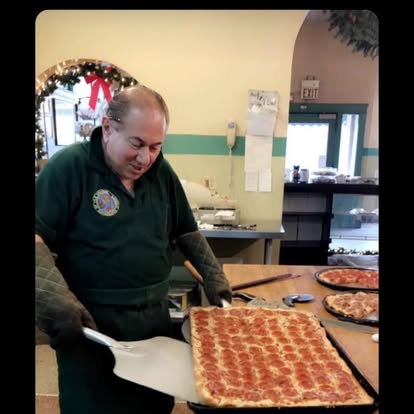 The owner sliding a pepperoni sheet pizza off the peel