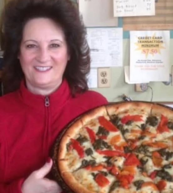 Fresh vegetable pizza held proudly behind the Messina counter